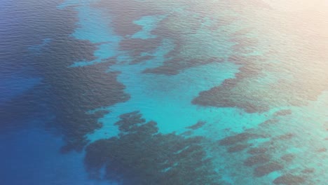Cinematic-Aerial-view-of-Caribbean-reef-,-turquoise-water-during-sunrise,-Roatan-island,-west-end,-Honduras,-Central-America