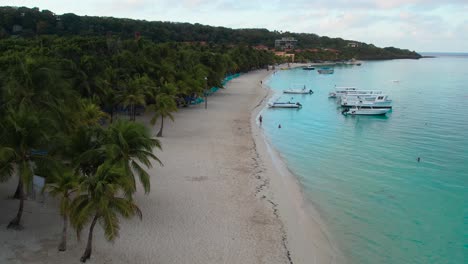 Cinematic-Aerial-view-of-Caribbean-coast-,-turquoise-water,-sandy-beach-during-sunrise,-Roatan-island,-west-end,-Honduras