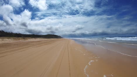 Rear-facing-driving-point-of-view-POV-of-a-deserted-Queensland-beach-under-a-blue-sky-with-white-cloud-banks---ideal-for-interior-car-scene-green-screen-replacement