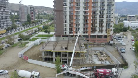 Mixer-Trucks,-Mobile-Crane,-And-Manual-Workers-During-Concrete-Pouring-Of-Slab-At-Construction-Site