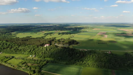 Shadows-of-clouds-sailing-through-green-and-vibrant-landscape-of-Lithuania,-high-angle-drone-view