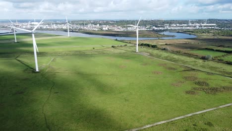 Aerial-view-flying-around-renewable-energy-wind-farm-wind-turbines-spinning-on-British-countryside-pan-right