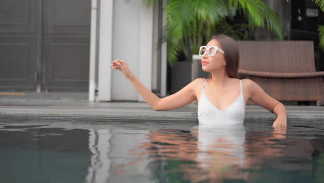 Classy-Slender-Exotic-Woman-With-Sunglasses-in-Swimming-Pool-of-Hotel-Resort,-Full-Frame