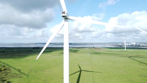 Aerial-view-flying-around-renewable-energy-wind-farm-wind-turbines-spinning-on-British-countryside-rising-shot