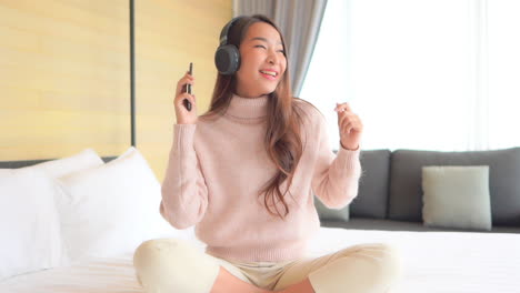 Hermosa-Mujer-Asiática-Escuchando-Música-Con-Smartphone-Y-Auriculares-En-El-Dormitorio