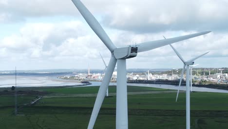 Alternative-green-energy-wind-farm-turbines-spinning-in-Frodsham-Cheshire-fields-aerial-view-closeup-orbit-left