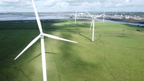 Aerial-view-flying-around-renewable-energy-wind-farm-wind-turbines-spinning-on-British-countryside-slow-right-orbit-shot