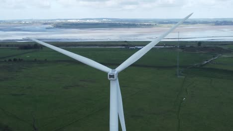Alternative-green-energy-wind-farm-turbines-spinning-in-Frodsham-Cheshire-fields-aerial-view-tilt-up