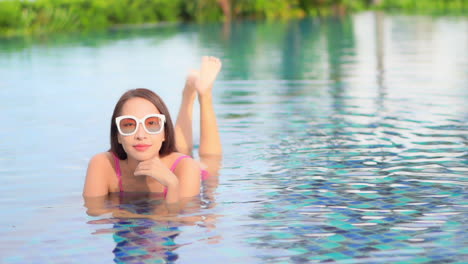 Happy-Exotic-Woman-Lying-in-Shallow-Water-of-Swimming-Pool,-Relaxing-and-Enjoying-on-Sunny-Summer-Day,-Full-Frame