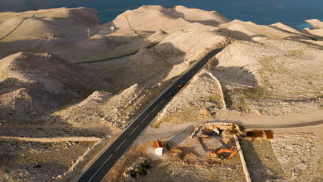 Aerial-View-Of-A-Car-Driving-On-The-Road-Towards-The-Sea-In-The-Island-Of-Pag-In-Croatia