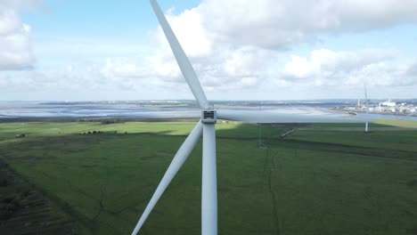 Alternative-green-energy-wind-farm-turbines-spinning-in-Frodsham-Cheshire-fields-aerial-view-closeup-pull-back