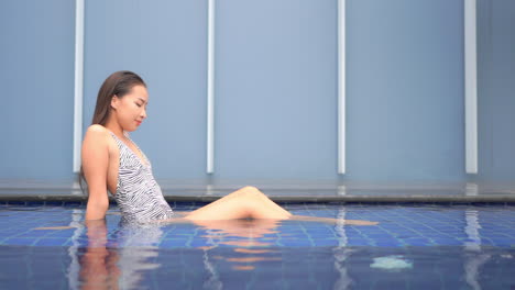 Sexy-young-asian-woman-enjoying-in-a-pool-water-of-luxury-hotel,-full-frame-slow-motion