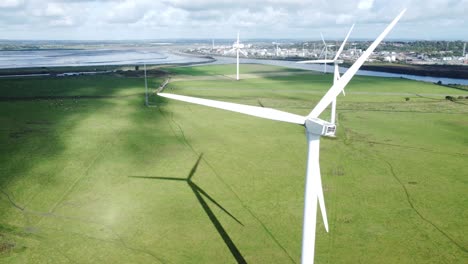 Aerial-view-flying-around-renewable-energy-wind-farm-wind-turbines-spinning-on-British-countryside-drifting-right