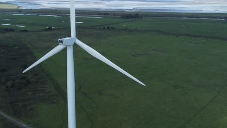 Aerial-view-flying-around-renewable-energy-wind-farm-wind-turbines-spinning-on-British-countryside-rear-shot