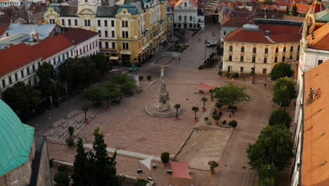 Plaza-Szechenyi-Vacía-En-La-Ciudad-De-Pecs,-Hungría-Con-La-Famosa-Estatua-De-La-Trinidad-Al-Amanecer