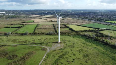 Aerial-view-flying-around-renewable-energy-wind-farm-wind-turbines-spinning-shadows-on-British-countryside