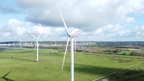 Aerial-view-flying-around-renewable-energy-wind-farm-wind-turbines-spinning-on-British-countryside-slow-descent