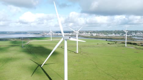 Aerial-view-flying-around-renewable-energy-wind-farm-wind-turbines-spinning-on-British-countryside-orbiting-left
