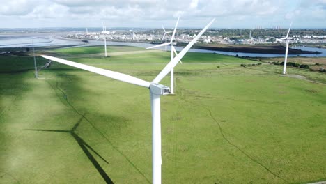 Aerial-view-flying-around-renewable-energy-wind-farm-wind-turbines-spinning-on-British-countryside-slow-right-dolly