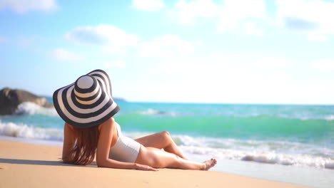 Unrecognizable-Caucasian-Brunette-Woman-in-Brim-Floppy-Sun-Hat-Lying-on-the-Sand-Seafront-when-Foamy-Waves-Rolling-Towards-Her-Feet,-vacation-copy-space-template