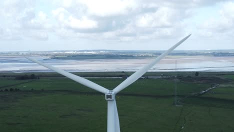 Alternative-green-energy-wind-farm-turbines-spinning-in-Frodsham-Cheshire-fields-aerial-view-descending