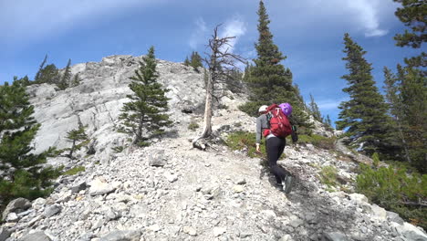 Woman-With-Backpack-on-Difficult-Hiking-Trail,-Climbing-Under-Rocky-Summit