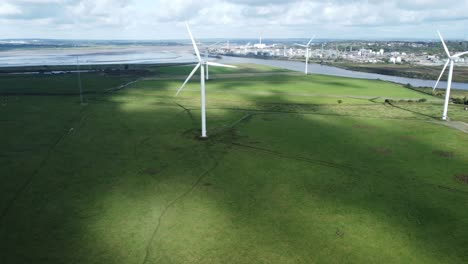 Aerial-view-flying-around-renewable-energy-wind-farm-wind-turbines-spinning-on-British-countryside-pan-left