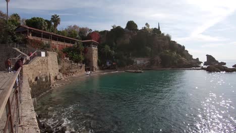 Wide-pan-shot-looking-over-the-shoreline-of-Turkey's-resort-city-of-Antalya,-bright-sunny-day-and-turquoise-ocean