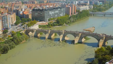 Aerial-View-Of-People-Crossing-At-Puente-de-Piedra-Over-Ebro-River-In-Zaragoza,-Aragon,-Spain