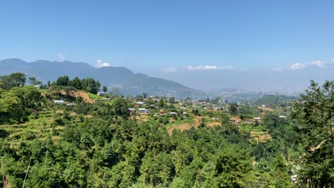 Ein-Blick-Auf-Ein-Kleines-Dorf-Auf-Einem-Hügel-Mit-Den-Himalaya-bergen-Im-Hintergrund-Mit-Schwenkblick