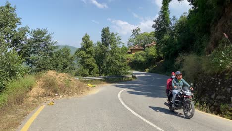 Lalitpur,-Nepal---October-12,-2021:-Motorcycles-driving-on-a-paved-road-in-the-mountains-with-the-Himalayan-Mountains-in-the-background