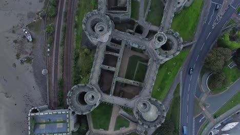 Conwy-medieval-castle-ruins-Birdseye-aerial-view-above-landmark-battlements-descending-overhead