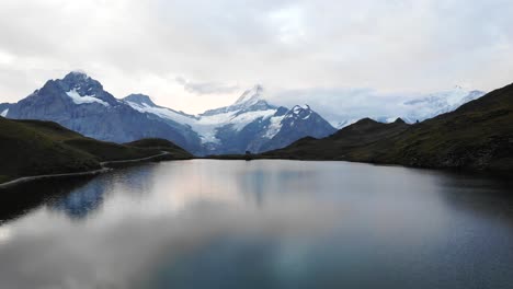 Sobrevuelo-Aéreo-Sobre-El-Lago-Bachalpsee-En-Grindelwald-Primero,-Suiza-Con-Vistas-Al-Schreckhorn-Y-Otros-Picos-Del-Oberland-Bernés-En-El-Reflejo