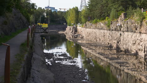 Tilt-up-shot-Reveal-Trollhätte-canal-low-water-levels-due-to-repair-work,-Sweden