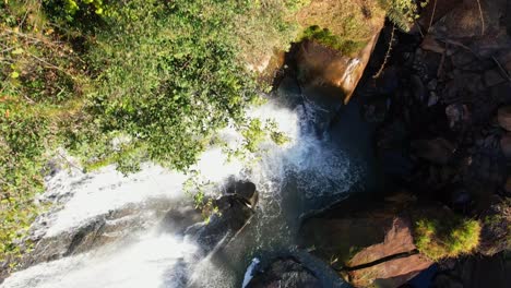 Drone-aerial-shot-from-forest-and-approaching-a-tropical-waterfall-In-Brazil-from-above-in-daylight-and-showing-the-water-with-a-colorful-rainbow