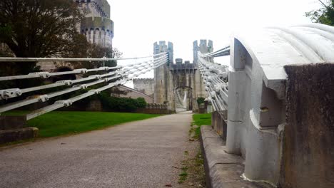 Conwy-castle-huge-steel-engineering-bridge-cables-low-angle-along-pathway-dolly-right