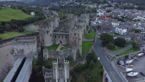 Medieval-Conwy-castle-walled-market-town-aerial-view-descending-tilt-up