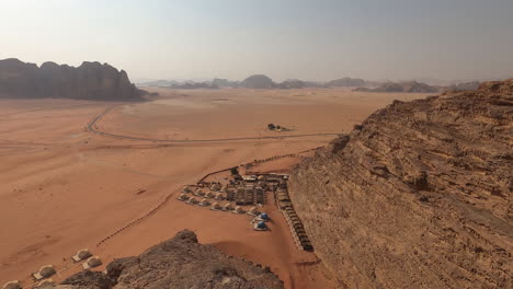 Wadi-Rum,-Jordan,-Lookout-View-of-Desert-Landscape-Steep-Cliffs-and-Bedouin-Camp-on-Hot-Sunny-Day