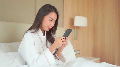 Pretty-Asian-woman-playing-games-on-her-phone-after-bath