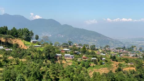 A-view-of-a-small-village-on-the-top-of-a-hill-with-the-Himalayan-Mountains-in-the-background-with-a-panning-view