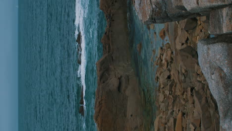 vertical-video-of-blue-atlantic-ocean-and-cliffs-of-the-Atlantic-Ocean-on-the-Island-Île-Grande-in-Pleumeur-Bodou,-France-Cote-D'amour