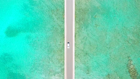 White-car-driving-in-Diakofti-Bridge-with-turquoise-water-background