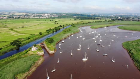 Scenic-Aerial-View-Of-Sailboats-Anchored-In-River-Exe-Beside-Green-Fields