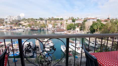 Cinematic-dolly-out-through-restaurant-balcony,-overlooking-at-old-city-marina-at-Antalya-Turkey