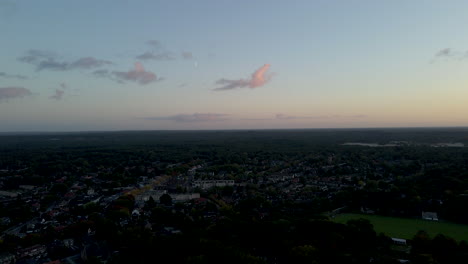Aerial-of-a-quiet-small-town-with-a-visible-moon-in-the-evening-sky