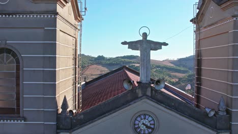 Orbital-aerial-shot-from-top-of-church-showing-christ-statue-and-blue-sky-and-mountains-in-the-background-with-sunlight-streak