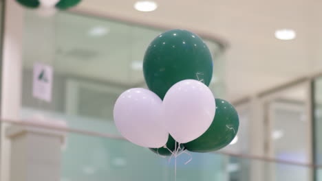 Grüne-Und-Weiße-Luftballons,-Die-Während-Einer-Veranstaltung-In-Einem-Firmenbüro-Festgebunden-Sind