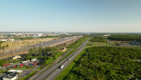 Aerial-flying-over-the-speedway,-freight-trucks-parking-lot,-cargo-railway-terminal-in-Gdansk-Poland-daytime-summer,-Drone-moves-forward