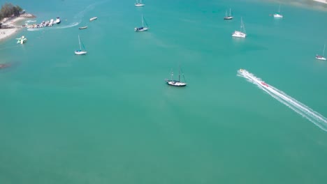 Luftaufnahmen-Von-Bananenbooten-Voller-Leute,-Die-Spaß-Haben-Und-Mit-Hoher-Geschwindigkeit-Auf-Einem-Motorboot-Fahren,-Wassersport