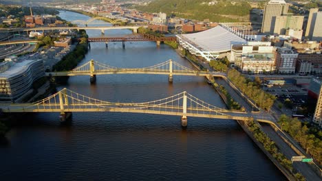Vista-Aérea-De-Drones-Sobre-Puentes-En-El-Río,-Hora-Dorada-En-Pittsburgh,-Estados-Unidos